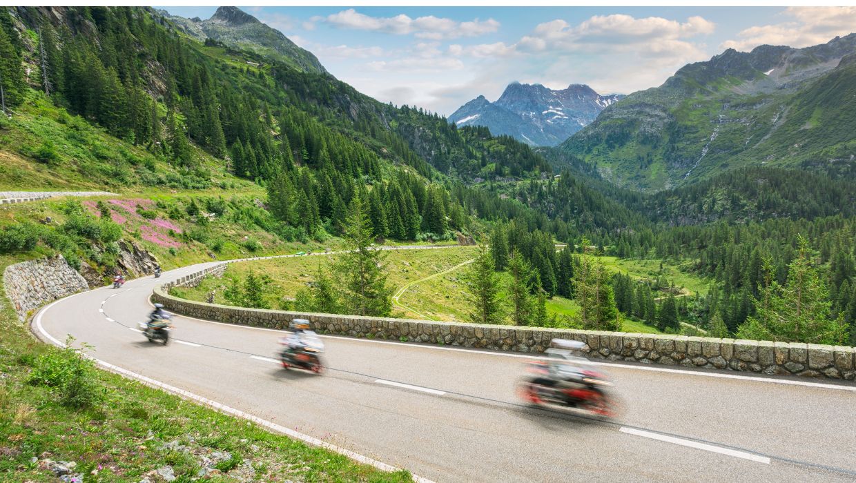 Motocykliści podróżujący krętą drogą wśród zielonych alpejskich krajobrazów Szwajcarii.